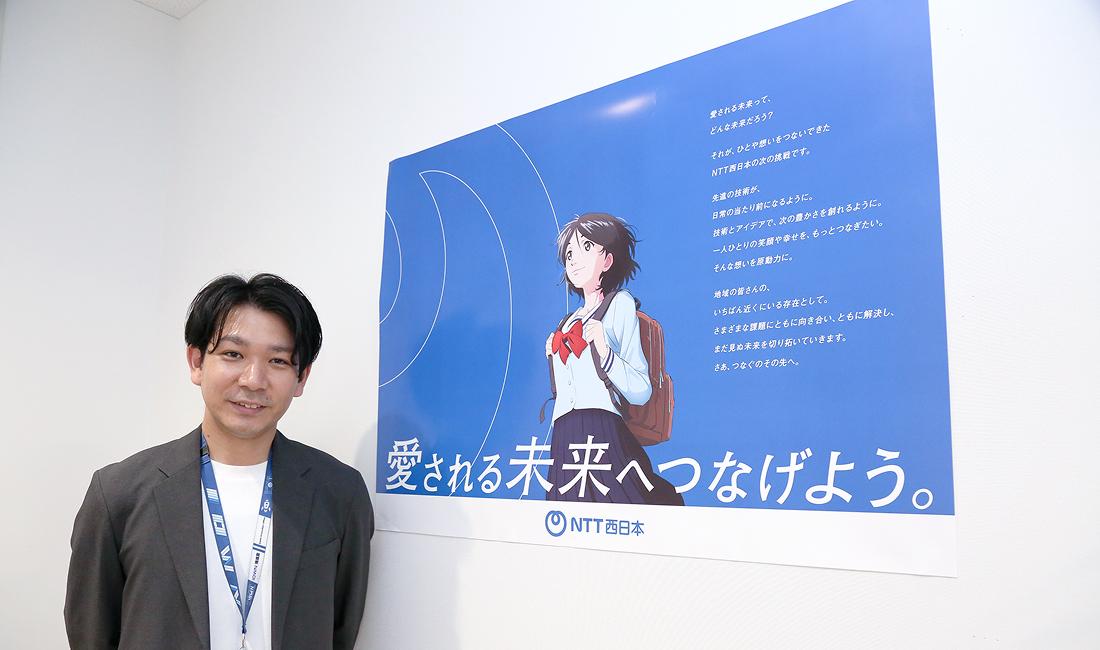 CMポスターの前に立つ仲宗根さん